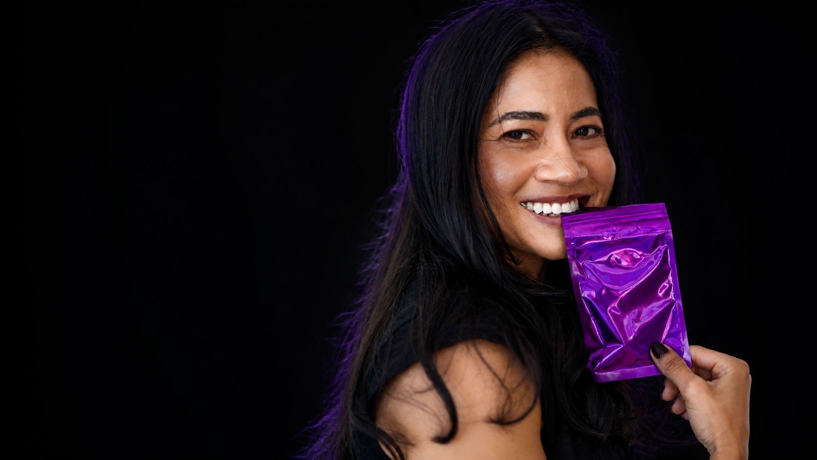 The founder of Lunatiq smiling and holding a metallic purple mystery package